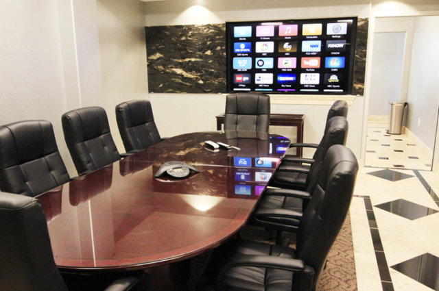 executive conference room with big table, chairs, and flat screen tv