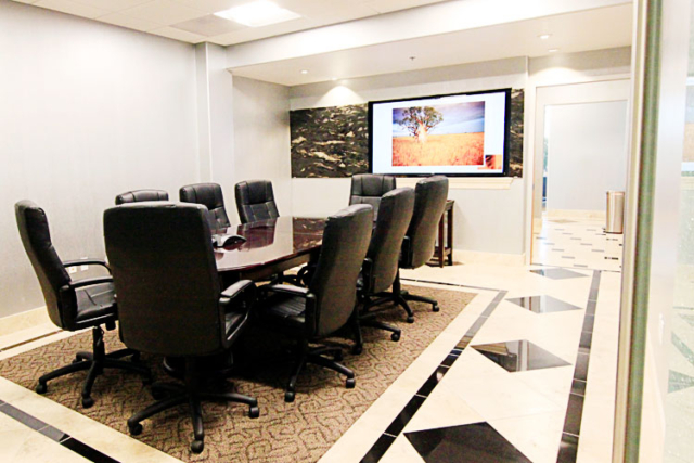 Conference room with big black chairs, a table, and flat screen tv