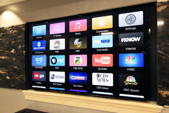 A 75 inch flat screen tv mounted on a conference room wall showing digital channels