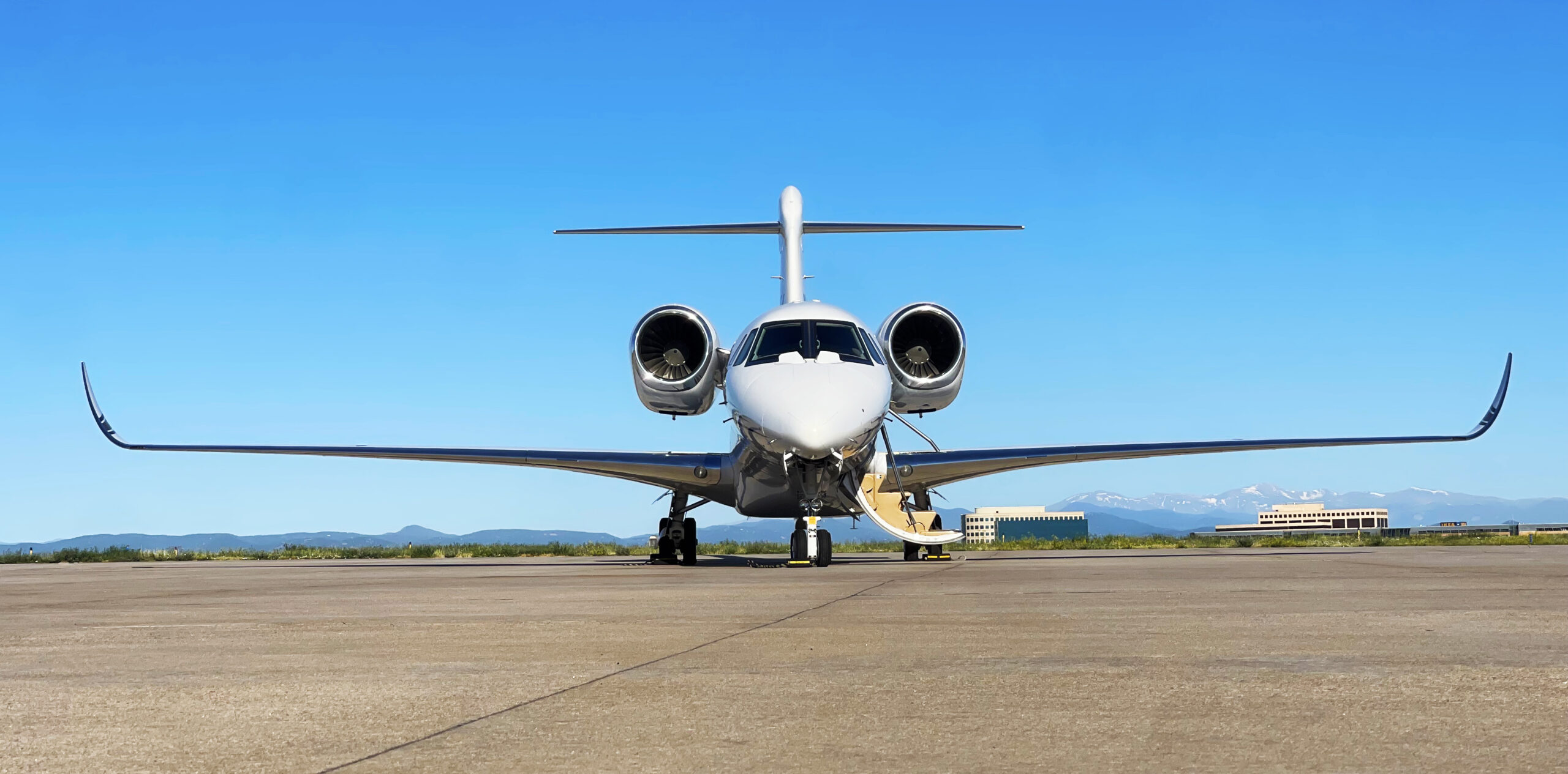 private jet on a runway with the stairs down on the right side of the aircraft